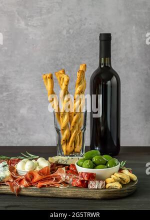 Antipasti a bordo con diversi antipasti italiani, formaggi, salumi, spuntini e vino. Foto Stock