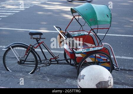 Becak sulla passeggiata laterale. Il becak e' uno dei tradizionali mezzi di trasporto indonesiani Foto Stock