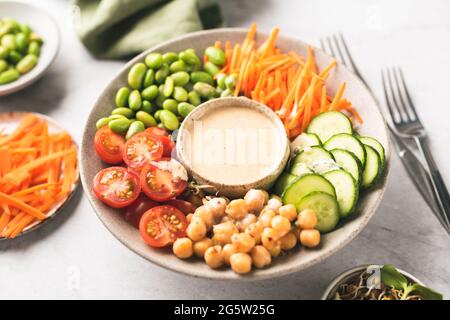 Ciotola di Buddha con salsa di anacardi, ceci, fagioli di edemame e verdure. Cibo vegano sano ricco di sostanze nutritive e fibre Foto Stock