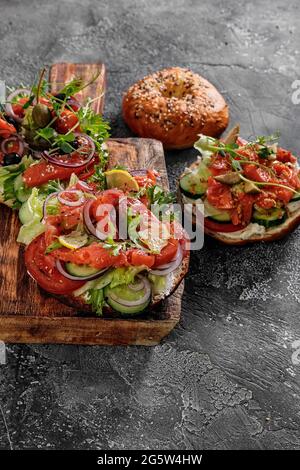 Insalata a sandwich a pallini verticali al bagel di New York con formaggio spalmabile, lattuga, cetriolo, capperi, cipolle e pesce rosso salato. La colazione era eccellente e deliziosa Foto Stock