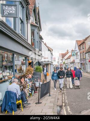 Un gruppo di giovani che passeggiano per il Buttermarket, Thame, Oxfordshire. Mentre altri godono un caffè all'aperto. Foto Stock