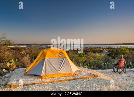 Camper che guarda il lago artificiale Amistad all'alba, campeggio Governors Landing, vicino a del Rio, Texas, USA Foto Stock