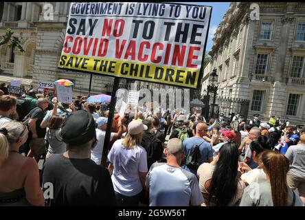 I manifestanti bloccano Whitehall, e si vede un grande striscione che dice 'il governo sta mentendo a voi dire no al vaccino Covid, Save the Children' durante la protesta. I manifestanti si riuniscono fuori Downing Street per protestare contro l'annuncio di Boris Johnson di un'estensione delle norme di blocco nel Regno Unito che ritengono violare i loro diritti umani, protestano anche contro il continuo uso di maschere e di essere sottoposti al programma di vaccinazione. Foto Stock