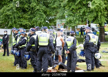 Londra, Regno Unito - 17 giugno 2021: Un protestante è detenuto dalla polizia durante lo sfratto del campo anti-lockdown di Shepherds Bush Green. Foto Stock