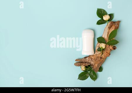 Composizione piatta con deodorante femminile naturale e legno con fiori rose su sfondo azzurro, spazio copia Foto Stock