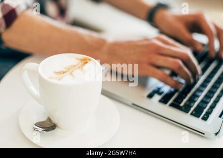 Uomo che lavora, utilizzando il laptop su un tavolo di legno, digitando le mani sulla tastiera, lavorando da casa o utilizzando internet per lo shopping online e i social network Foto Stock