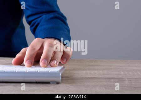 Primo piano di uomo d'affari caucasico che scrive sulla tastiera, isolato su sfondo grigio Foto Stock