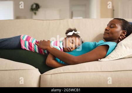 Felice madre afroamericana e figlia che si rilassano, sdraiati sul divano Foto Stock