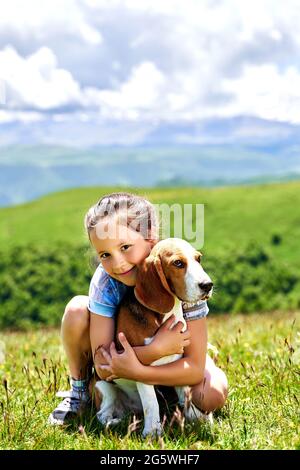 bambina divertente con un cane in montagna Foto Stock