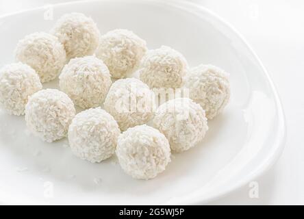 Tartufi di cocco bianchi dolci su sfondo bianco, fuoco selettivo. Foto Stock