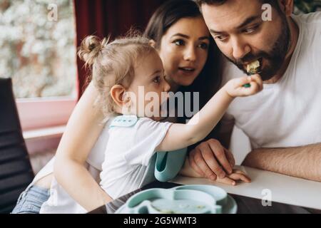 Il bambino nutre il padre con il cucchiaio. Foto Stock