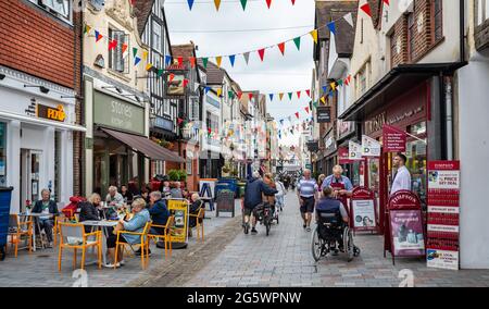 I bevitori di caffè all'aperto a Butchers Row festooned con il bunting a Salisbury, Wiltshire, Regno Unito il 29 giugno 2021 Foto Stock