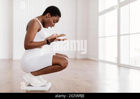 Ritratto della donna afroamericana usando le scale del bagno. Dimagrimento Foto Stock