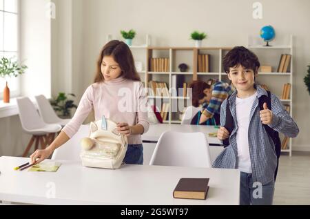 Il ragazzino elementare mostra il pollice in su come un segno di completamento riuscito della lezione. Foto Stock