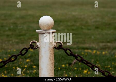 Vecchio stanchion di recinzione di catena di metallo con recinzione di catena in un parco di campagna Foto Stock