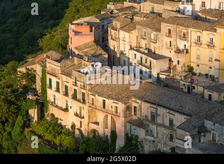 Ragusa, Sicilia, Italia. Vista sui tetti panoramici di Ragusa Ibla, tramonto, case aggrappate a ripide colline sopra gola boscosa. Foto Stock