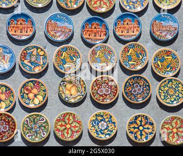 Noto, Siracusa, Sicilia, Italia. Calamite da frigorifero dai colori vivaci esposte all'esterno di un tipico negozio di souvenir in corso Vittorio Emanuele. Foto Stock