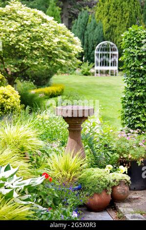 Bagno di uccello di pietra in un giardino di campagna inglese Foto Stock