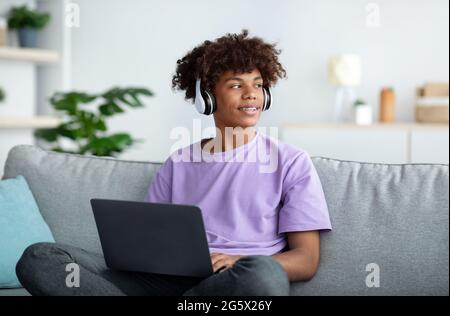 Formazione a distanza. Adolescente nero in cuffia che ha una conferenza online o una lezione remota sul computer portatile a casa Foto Stock