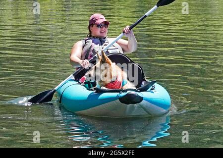 Una donna in kayak con il suo cane da pastore tedesco in una calda giornata estiva al lago Suttle nelle Cascades dell'Oregon centrale. Foto Stock