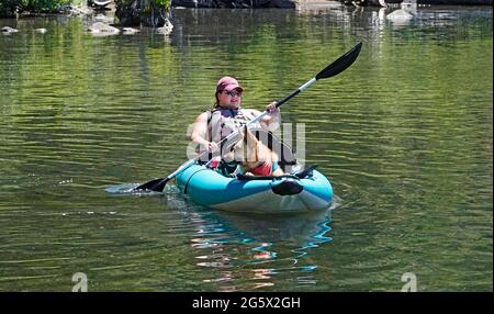 Una donna in kayak con il suo cane da pastore tedesco in una calda giornata estiva al lago Suttle nelle Cascades dell'Oregon centrale. Foto Stock