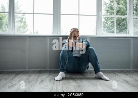 L'uomo si sente depresso e disperato, piangendo da solo a casa, sofferenza, dolore emotivo Foto Stock