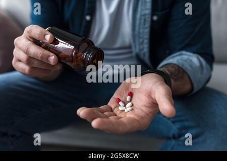 Manciata di pillole bianche nel palmo dei pazienti di sesso maschile. Sanità, trattamento, farmaci e depressione, dolore e suicidio Foto Stock