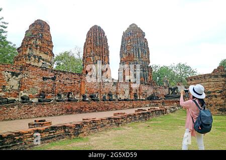 Visita femminile Foto di Stupas e Buddha immagini rovine nel tempio antico di Wat Mahathat, Ayutthaya Historical Island Thailandia Foto Stock