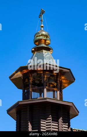 Pittoresco campanile di una chiesa ortodossa in legno con tetto dorato e croce. Foto Stock