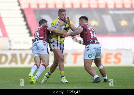 Mike Cooper (10) di Warrington Wolves è affrontato da Sam Powell (9) di Warriors Wigan e Ollie Partington (14) di Warriors Wigan Foto Stock