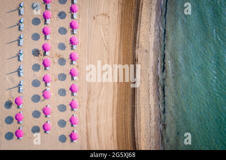 Vista aerea su una fila di ombrellone sul mare. Vista tipica di una località turistica nel sud di una destinazione turistica. Foto Stock