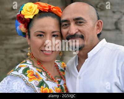 Vestito in su la coppia messicana di Yucatecan (uomo e donna) con i hairstyles tradizionali indossa i vestiti folkloric e sorrisi per la macchina fotografica. Foto Stock