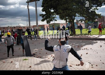 Bogotà, Colombia. 29 Giugno 2021. Un dimostratore getta rocce e debree alla polizia sommossa della Colombia (ESMAD) come popolo di Fontanar - Suba a Bogotà, Colombia protestò e si scontrò contro la polizia sommossa della Colombia (Escuadron Movil Antiurbios ESMAD) contro la visita del presidente della Colombia Ivan Duque Marquez ad un parco dove il sistema della metropolitana di Bogotà sarà costruito, Tra due mesi di proteste anti-governative contro il presidente Ivan Duque Marquez, disuguaglianze e disordini di polizia durante le proteste, il 29 giugno 2021. Credit: Long Visual Press/Alamy Live News Foto Stock