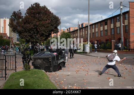 Bogotà, Colombia. 29 Giugno 2021. Un dimostratore getta rocce e debree alla polizia sommossa della Colombia (ESMAD) come popolo di Fontanar - Suba a Bogotà, Colombia protestò e si scontrò contro la polizia sommossa della Colombia (Escuadron Movil Antiurbios ESMAD) contro la visita del presidente della Colombia Ivan Duque Marquez ad un parco dove il sistema della metropolitana di Bogotà sarà costruito, Tra due mesi di proteste anti-governative contro il presidente Ivan Duque Marquez, disuguaglianze e disordini di polizia durante le proteste, il 29 giugno 2021. Credit: Long Visual Press/Alamy Live News Foto Stock