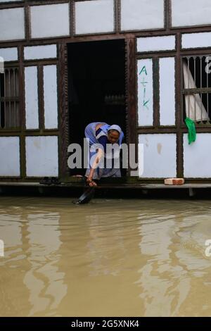 Una donna lava il vaso in acqua durante l'alluvione monsonica a Munshiganj, vicino a Dhaka, Bangladesh, il 28 luglio 2020. Oltre 9.6 milioni di persone sono state colpite da inondazioni monsoniche, devastando vaste aree dell’India, del Bangladesh e del Nepal. Foto Stock