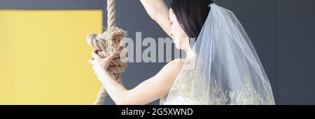 Donna in abito da sposa tiene la sua mano su anello per collo Foto Stock