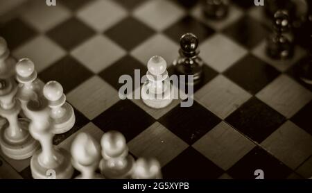 Due scacchi sono pedine: Nere e bianche. Pezzi di scacchi in legno sulla scacchiera, vista dall'alto. Gioco intellettuale - scacchi. Pezzi di scacchi sulla tavola. R Foto Stock