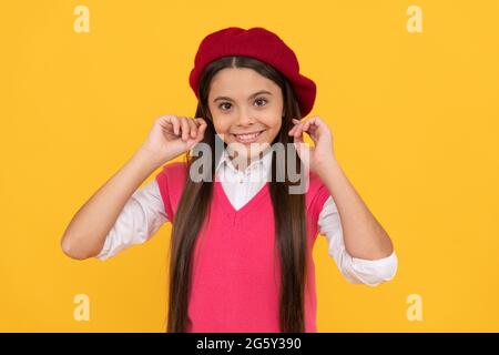 felice teen ragazza scuola in beret francese su sfondo giallo, bellezza Foto Stock