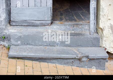 scalini di cemento ingresso alla vecchia casa con una porta di legno soglia del palazzo sulla discesa del marciapiede pedonale da piastrelle di pietra vicino Foto Stock