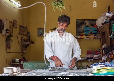 Maschio indiano usando il ferro elettrico tradizionale vecchio stile industriale a vapore su indumenti, Puducherry (Pondicherry), Tamil Nadu, India Foto Stock