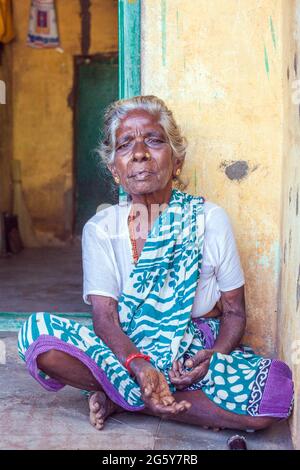 Ritratto di anziana signora indiana con i capelli grigi seduti nella porta - pregando con mano estensibile, Puducherry (Pondicherry), Tamil Nadu, India Foto Stock