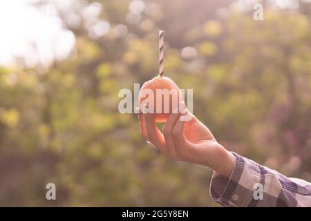 Giovane Azienda e bere la frutta di arancia con il tubicino in esso inserito Foto Stock