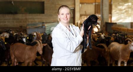 Agricoltore femminile che si prende cura di goatlings Foto Stock