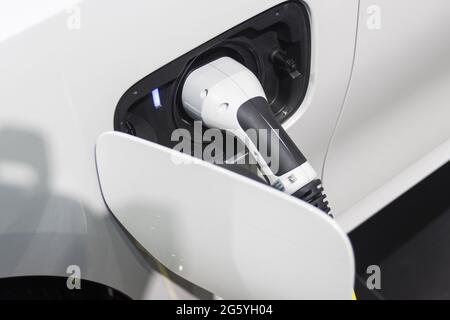 La ricarica della batteria per le nuove innovazioni automobilistiche l'alimentatore inserito in un'auto elettrica in fase di ricarica Foto Stock