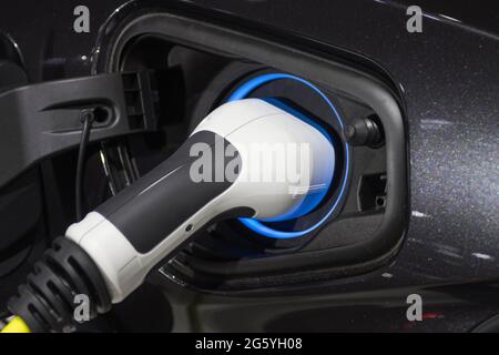 La ricarica della batteria per le nuove innovazioni automobilistiche l'alimentatore inserito in un'auto elettrica in fase di ricarica Foto Stock