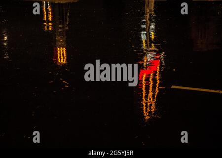 Riflessione distorta di un segno di McDonalds in pozze di notte Foto Stock