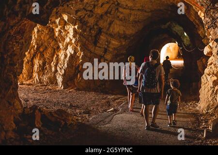 I turisti che esplorano il Tunnel si sono ritagliati nelle scogliere rocciose sul mare sul sentiero pedonale nella baia di Petrovac in Montenegro Foto Stock