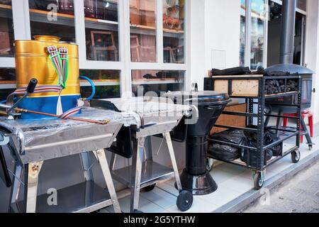 Le nuovissime griglie per barbecue, i carbonai e uno spruzzatore per zaino disinfettante in vendita sono esposti all'esterno di un negozio rurale. Foto Stock