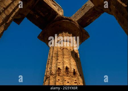 Il luminoso sole del mattino rivela dettagli in pietra e macchie di stucco originale su colonne doriche e capitelli snocciolati e scanalati ad un angolo del colonnato ricostruito del Tempio e, probabilmente dedicato alla dea Hera, nell'antica città greca e porto di Selinus o Selinous a Selinunte, nella Sicilia sud-occidentale, Italia. Anche se il tempio probabilmente crollò in terremoti dopo l'abbandono di Selino, fu ricostruito nel 1958 utilizzando i materiali originali. Foto Stock