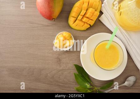 Bicchiere con succo di mango servito su un piatto su un tavolo di legno con frutta e porzioni. Vista dall'alto. Foto Stock